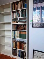 Full view of white bookcases showing multiple shelves filled with books