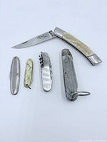 All five folding knives laid out, blades closed except one open