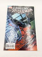 Amazing Spider-Man comic in bag, issue number partially visible, cover shows Spider-Man crashing through glass