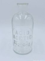 Front view of clear glass bottle showing etched label ACID ACETIC HC2H3O2