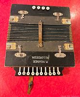 Top view closed bellows, shows M. Hohner branding, 10 treble buttons, 5 smaller buttons, corner decals