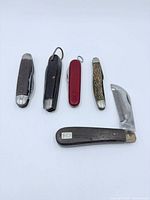 All five folding knives displayed closed, comb knife open