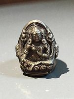 Front view of silver ring showing raised Buddha design