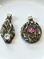 Front view of both pendants showing textured surfaces and gemstones