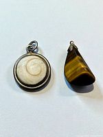 Front view of both pendants: round shell in sterling bezel and tiger's eye stone pendant