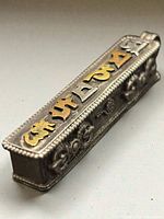 Full side view showing mixed-metal script, beaded edges and floral relief