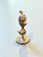 Front view of sterling silver bird charm next to coin for scale