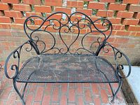 Front view of wrought iron 2-seat bench showing scrollwork back, mesh seat, arm details and overall wear