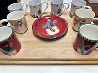 Seven mugs and one plate displayed on wooden board