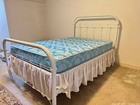 Full view of assembled white metal full bed frame with mattress for scale