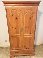 Front view of closed Lane armoire showing two paneled doors and lower drawers