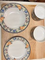 Two dinner plates and two bowls arranged on board