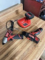 Impact driver, drill/driver, charger with battery pack displayed on work surface