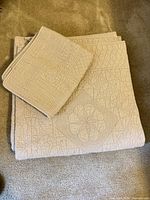 Folded quilt with pillow shams displayed on floor