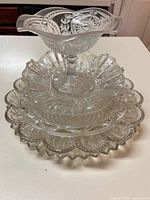 Stack of all five clear pressed glass pieces showing compote on top and four bowls/plates beneath