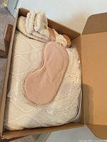 Box contents showing blanket, eye mask, fuzzy socks