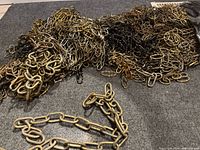 Pile of assorted metal link chains on grey carpet