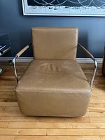 Front view of tan leather lounge chair showing seat wear and chrome arms