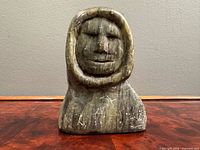 Front view of stone bust showing Inuit face in hood