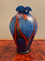 Front view showing blue body, red-orange trails, black foot