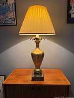 Full view of illuminated lamp with shade on wooden surface
