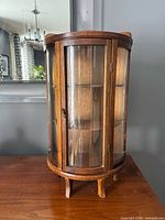 Front view of miniature wood curio cabinet with curved glass door and shelves