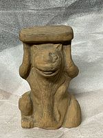 Front view of clay animal figure holding slab