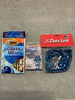 Front view of three sealed items: microfiber cloth, rain poncho, chain lock