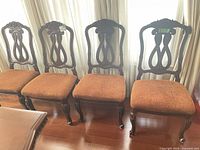 Four carved wood dining chairs side by side