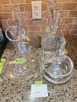 Group of four decanters and lidded jar on countertop