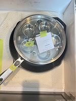 Stainless egg poacher pan resting inside cast iron skillet showing four cups