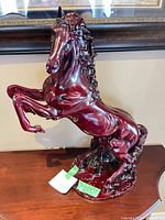 Full view of burgundy rearing horse sculpture on table