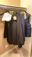 overview of three jackets and pair of shoes hanging in closet