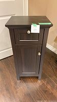 Front view of dark wood cabinet showing drawer and door