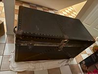 Full view of closed steamer trunk showing lid, latches, riveted edging