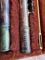 Close-up of flute barrel inside case, showing Artley engraving, tarnish, cleaning rod, and plush interior lining
