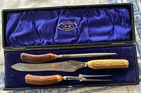 Set displayed in open case showing knife, fork, steel, blue silk lining