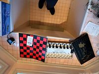 Open Gallant Knight chess box showing red-black folding board and sorted black/white pieces; Ten-Q box visible at left