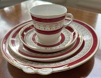 Stacked Wedgwood Ulander Powder Ruby place setting showing cup, saucer and three plates