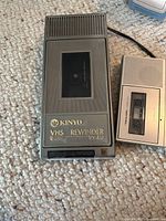 Top view Kinyo UV-413 VHS rewinder beside cassette recorder