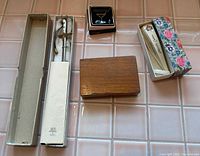Group view of letter opener in box, cocktail tray, wooden box, fan in sleeve