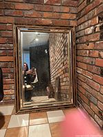 Front view of ornate mirror leaning against brick wall
