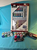 Overall view showing sealed watercolor kit, Jacquard paint jars, Grumbacher set, and fabric markers