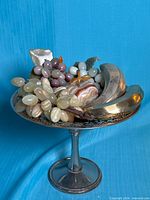 Pedestal bowl holding assorted stone fruit and metal bananas