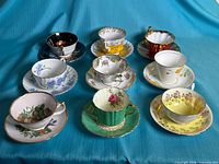 All nine teacup and saucer sets arranged on blue cloth