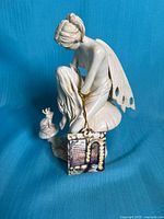 Front left view of ivory-tone fairy figurine on mushroom facing crowned frog