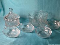 Group shot of all six glass pieces including pressed bowl, lidded bowl, four fruit dishes