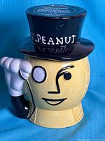 Front view of ceramic Mr. Peanut cookie jar showing face, monocle, saluting arm and top-hat lid