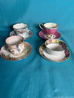 Front view of all four teacup and saucer sets on blue backdrop