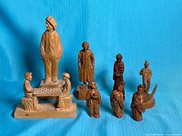 Full group of eight wooden figurines on blue backdrop